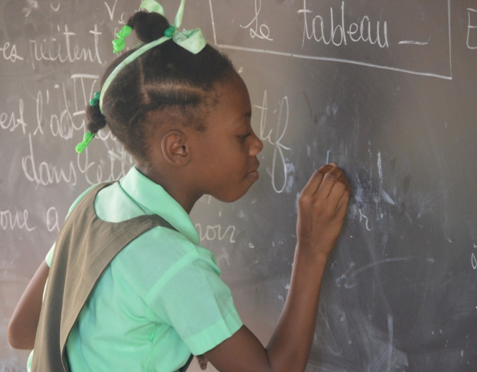 Photo of 4th grade girl at the chalkboard in a Grand Goave Classroom.
